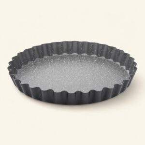 Czarna forma do tarty z falistymi krawędziami, idealna do pieczenia i serwowania wypieków, wykonana z wysokiej jakości materiałów ceramicznych i metalowych.